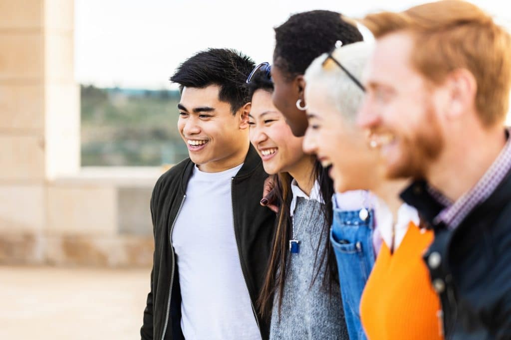 Diverse group of united young friends laughing together outdoor